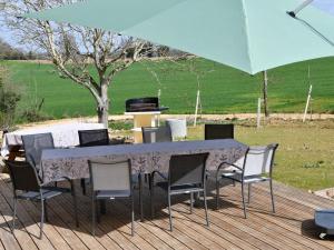 a table and chairs under a large blue umbrella at Gîte rénové avec piscine intérieure, accessible PMR, en plein cœur du Bocage Vendéen. - FR-1-426-536 in Cheffois