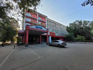 un coche aparcado en un aparcamiento frente a un edificio en Гостиница ИЛЕК, en Aktobe