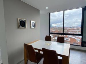 une salle à manger avec une table, des chaises et une grande fenêtre dans l'établissement Amplio apartamento con excelente vista, à Bogotá