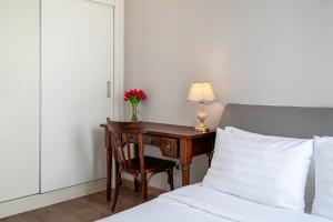 a bedroom with a desk with a vase of flowers at Vinhomes Central Park Apartments Luxury For Rent in Ho Chi Minh City