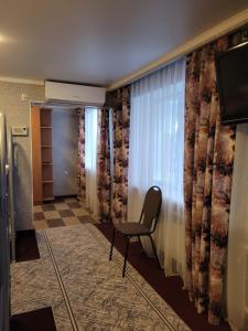 einen Stuhl in einem Zimmer mit Fenster in der Unterkunft Гостиница ИЛЕК in Aqtöbe