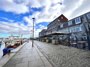 a dock with a building and a boat on the water at Stylish apartment, Barbican in Plymouth