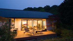 a house with a deck with chairs and a table at Fugaku Gunjo in Izu