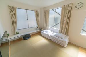 een woonkamer met ramen en een klok aan de muur bij Flower Base Lily House in Fukuoka