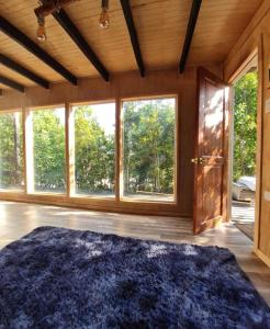 a large room with a large blue rug in a room with windows at Lodge in the Woods in Puerto Montt