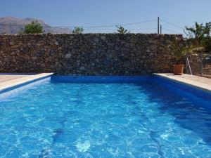 a swimming pool in front of a stone wall at Finca La Rana Verde in Cortes de la Frontera
