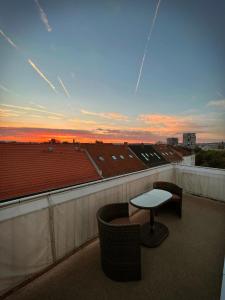 a balcony with a table and chairs and a sunset at Talgarten Penthouse 1 in Erfurt