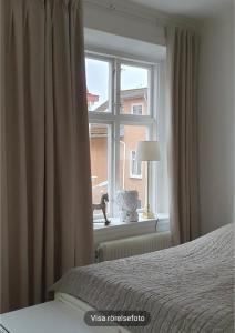 Dormitorio con ventana, cama y lámpara en Centrum lägenhet, en Skövde