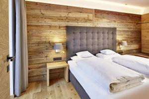 two beds in a bedroom with wooden walls at der grüne Baum Mountain Boutique Hotel in Ehrwald