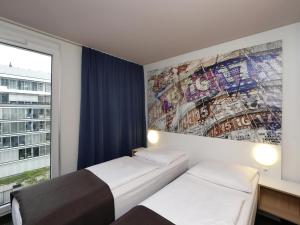 a room with two beds and a wall with a mural at B&B HOTEL Berlin-Alexanderplatz in Berlin