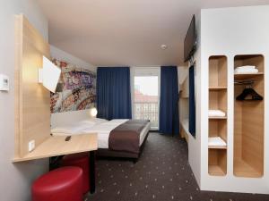 een hotelkamer met een bed, een bureau en een raam bij B&B HOTEL Berlin-Alexanderplatz in Berlijn