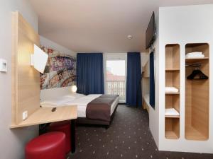 a hotel room with a bed and a desk and a window at B&B HOTEL Berlin-Alexanderplatz in Berlin