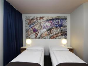 duas camas num quarto com um mural na parede em B&B HOTEL Berlin-Alexanderplatz em Berlim
