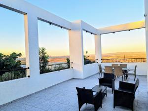 un patio con tavoli, sedie e vista sull'oceano di וילה אקרופוליס Villa Acropolis a ‘En Dor