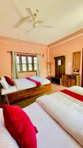 a bedroom with two beds with red pillows at Hotel Tree Tops- A Serene Friendly Hotel in Sauraha in Chitwan