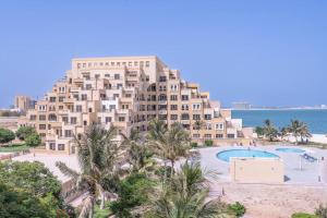 a large apartment building with a pool and palm trees at Contemporary Living by The Sea & 2BD & New Listing in Ras al Khaimah