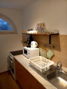a kitchen counter with a sink and a microwave at Idill Apartmanház B&B in Tiszafüred