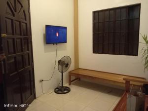 a room with a tv and a fan and a window at Estrelle Orange House - Backpackers Hub in Puerto Princesa City