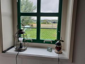 a window with a green frame and a lamp on a window sill at slapen aan de voet van de molen in Ovezande +35 photos