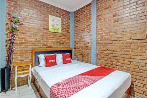 een slaapkamer met een bakstenen muur en een bed met rode kussens bij OYO 92606 Djoglo Boto Homestay Syariah in Yogyakarta