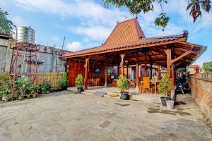 een houten paviljoen met tafels en stoelen op een binnenplaats bij OYO 92606 Djoglo Boto Homestay Syariah in Yogyakarta