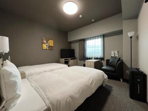 ein Hotelzimmer mit 2 Betten und einem Stuhl in der Unterkunft Hotel Route Inn Kato in Kato