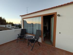 een balkon met 2 stoelen en een glazen schuifdeur bij La Morada in Artenara