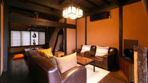 a living room with leather furniture and a chandelier at 森の入り江の離れ宿 無雙庵枇杷 in Toi