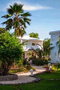 a white house with a palm tree and a garden at Diamonds Mapenzi Beach in Kiwengwa