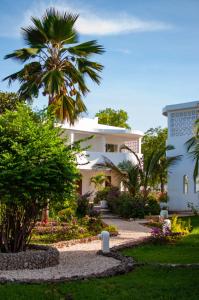 a white house with a palm tree and a garden at Diamonds Mapenzi Beach - All Inclusive in Kiwengwa
