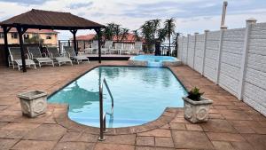 a swimming pool with chairs and a gazebo at Cassa De La Luna Diossa in Kingsburgh