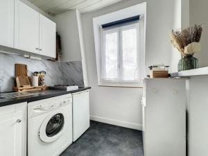 une cuisine blanche avec un lave-linge et une fenêtre dans l'établissement Joli et lumineux studio proche Paris, à Charenton-le-Pont