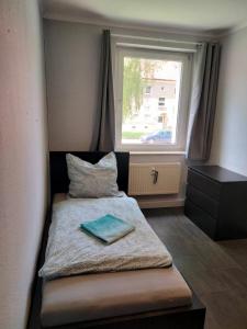 a small bedroom with a bed with a window at 5-Bett-Wohnung in Glöthe, Staßfurt in Staßfurt