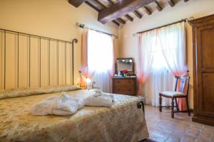 a bedroom with a bed and a chair and windows at Hotel & SPA L'Antico Forziere in Deruta