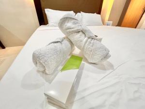 a pair of towels on a bed with a green book at Newport Hotel near NAIA Manila Airport Terminal Pasay in Manila