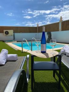 una botella de vino sentada en una mesa con dos copas en Beach Villa private heated pool, en Caleta de Fuste