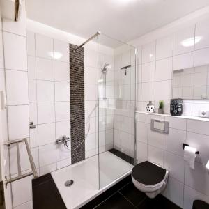 a white bathroom with a shower and a toilet at Apartment Köln Rath in Cologne