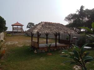 una capanna con tetto in paglia e gazebo di Rumah Pantai Krui a Wainapal