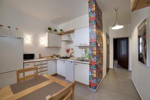 ソポトにあるMajowe Apartamentyの白いキャビネットとカラフルなモザイクの壁が備わるキッチン