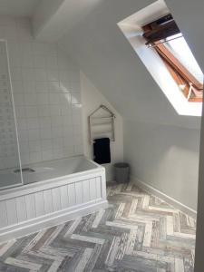 a bathroom with a tub and a tile floor at Honey Cottage in Totland