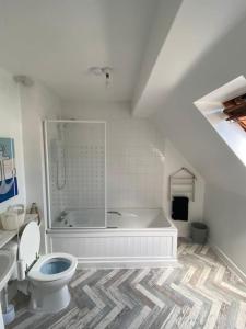 a white bathroom with a tub and a toilet at Honey Cottage in Totland