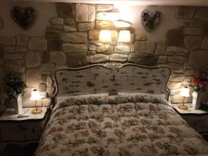 1 dormitorio con pared de piedra, 1 cama y 2 lámparas en Casa Samuela 