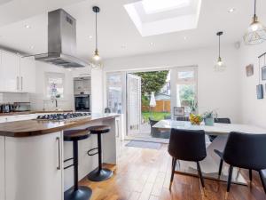 a kitchen with white cabinets and a table with stools at Willow Road Enfield Town Greater London in Enfield