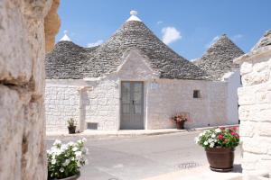 een wit stenen gebouw met een grijs dak met bloemen bij Trulli Soave in Alberobello