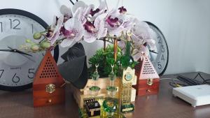 a vase of flowers on a table with clocks at D Casa Cattleya Desaru in Kota Tinggi