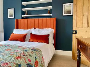 a bedroom with a bed with an orange headboard and red pillows at Cotswold Home over 4 floors - perfect for Families Friends Contractors in Chipping Norton