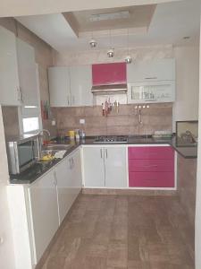 a kitchen with white and pink cabinets and a wooden floor at Les Jasmins de Hammamet in Hammamet