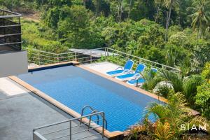 a swimming pool with two blue chairs and trees at Chaweng Hill 2Br in Koh Samui