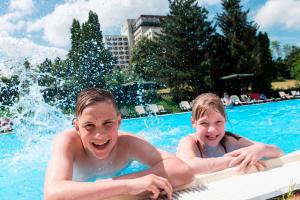 dwoje młodych ludzi bawiących się w basenie w obiekcie AHORN Berghotel Friedrichroda w mieście Friedrichroda