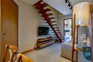 un salon avec un escalier et une télévision dans l'établissement Conforto e comodidade em Praia do Forte, à Mata de São João